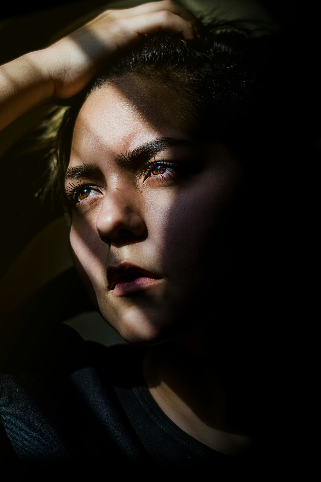 Portrait of a young woman looking up in dramatic light